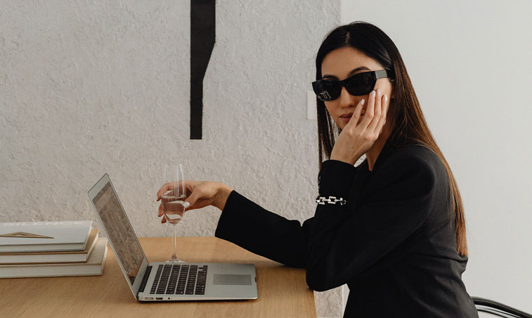femme qui tient une coupe de champagne devant un ordinateur